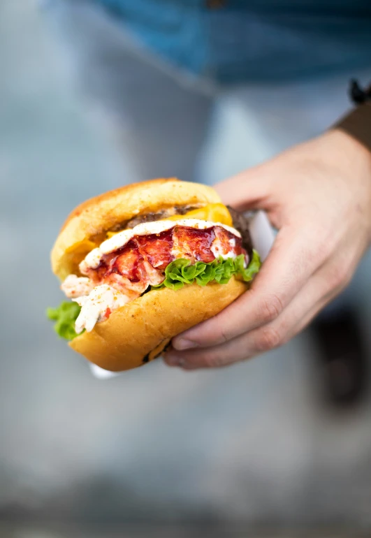 a hand holding a large sandwich with meat and vegetables