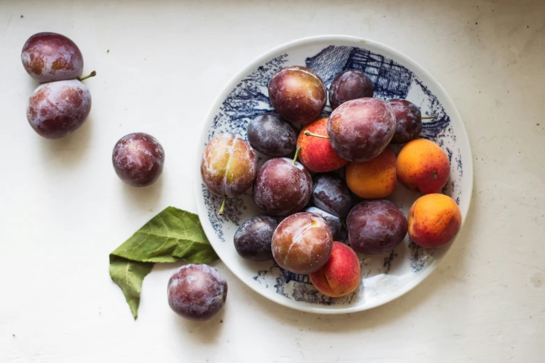 a bowl full of fruit sitting next to a couple of leaves