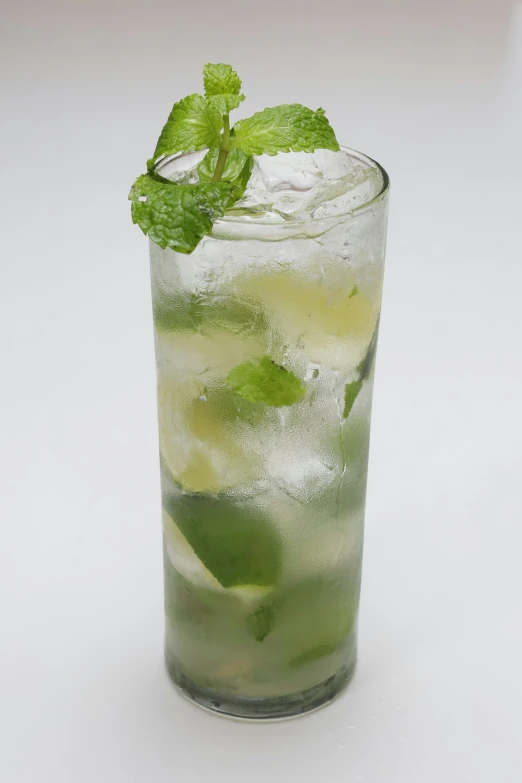 a green mojito with ice and lime on a white background