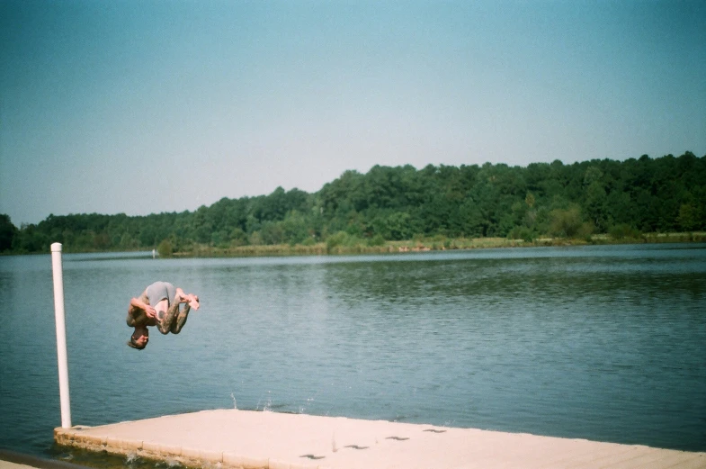 a man is doing a back flip over the water