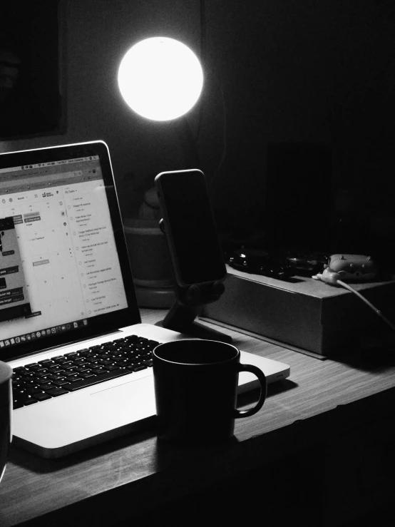 a computer desk with a laptop, coffee cup and phone in it