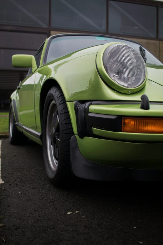 an old green sports car parked on the street