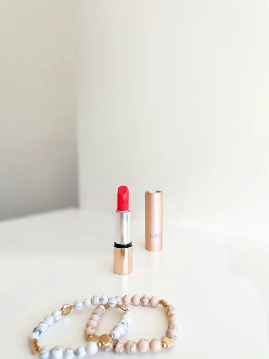 two red lipstick, a celet and a watch on a table