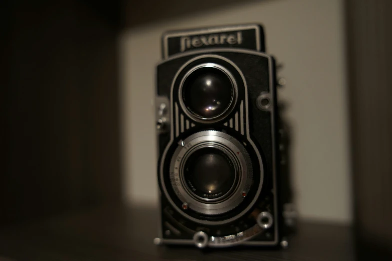 an old camera on a wooden table with the lens facing the right