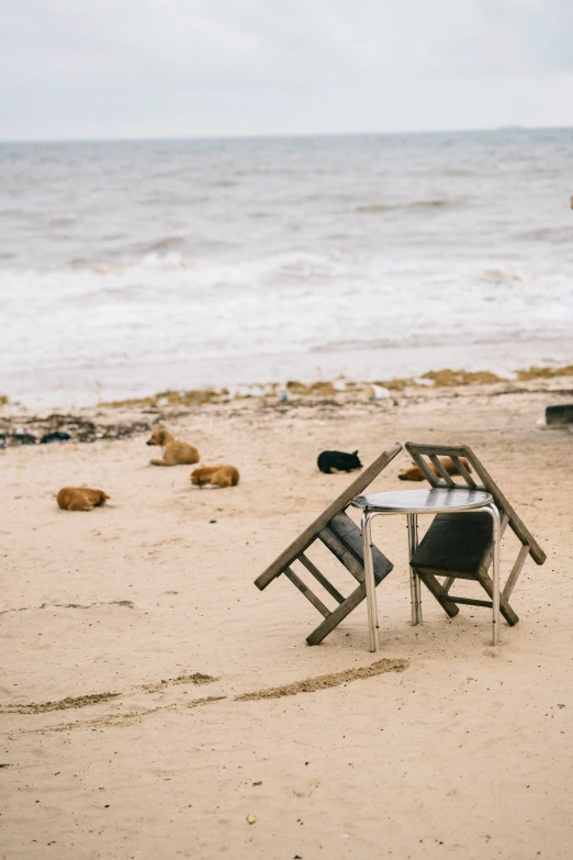 a table and chair on the beach in front of the ocean