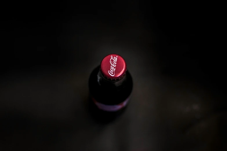 a red soda bottle with its cap slightly upside down