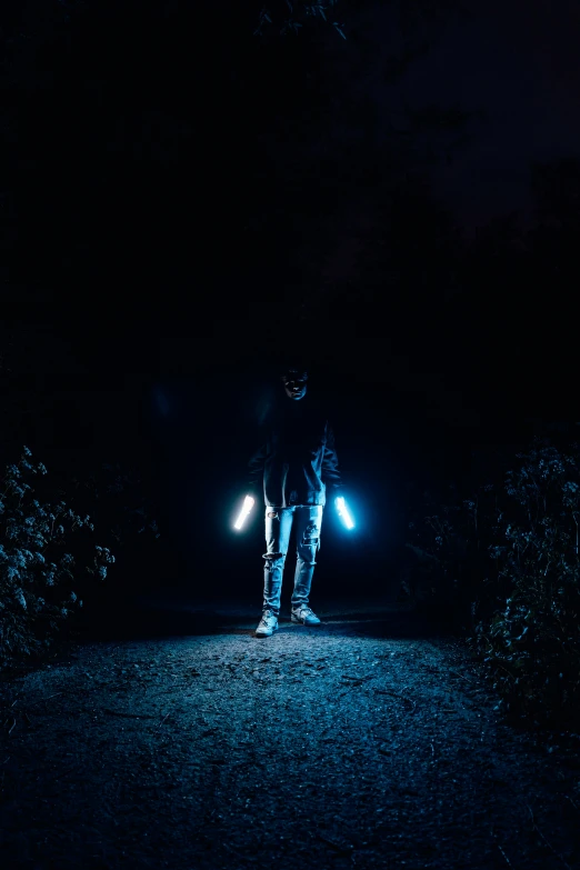 two people stand on a road at night with headlights