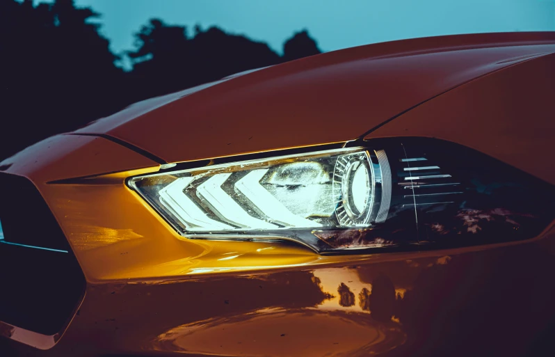 the front headlight of a car with a tree in the background