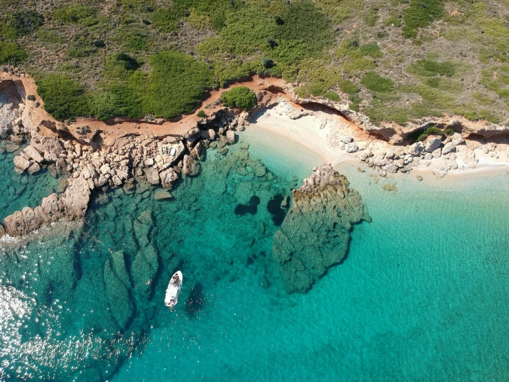 aerial view of rocks along shore with blue water