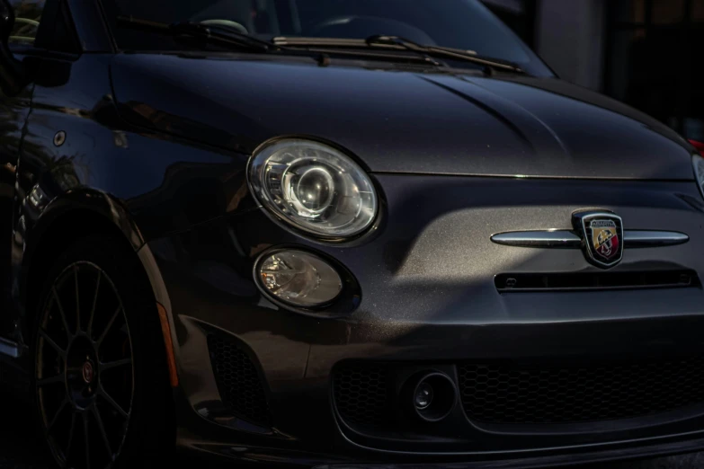 the front of a black mini car parked next to a building