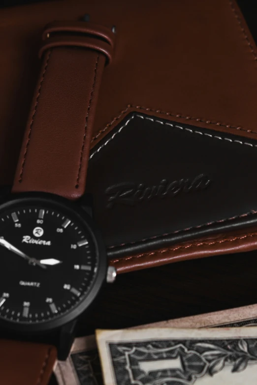 a watch sits in front of money and on a brown leather bag