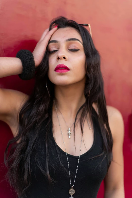 a beautiful woman in a black dress posing with her hand on her head