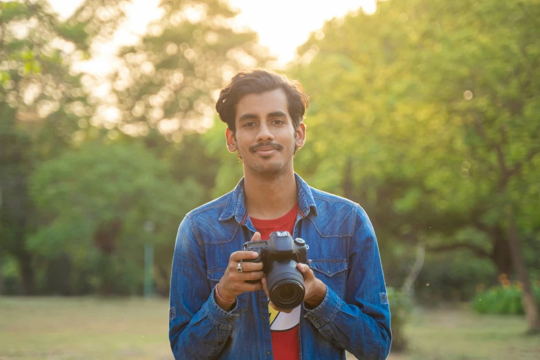 a young man holding a camera at sunset