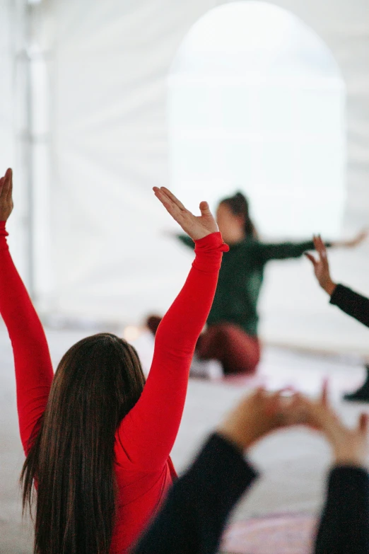 a woman with her arms stretched out in the air while people hold their hands high up