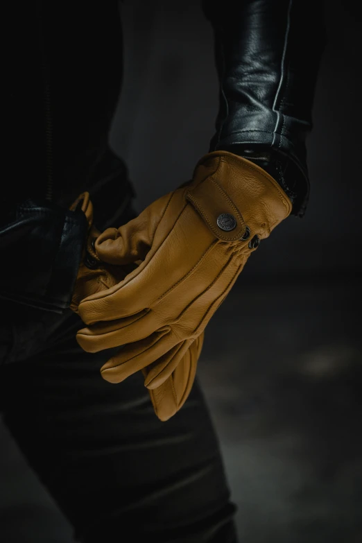 someone in black and brown gloves holds their wrist with two hands