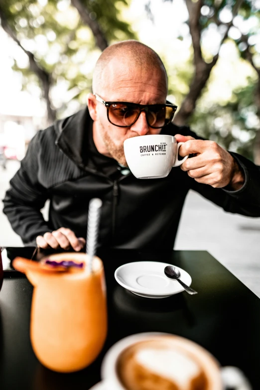 a man in glasses sitting at a table with his coffee