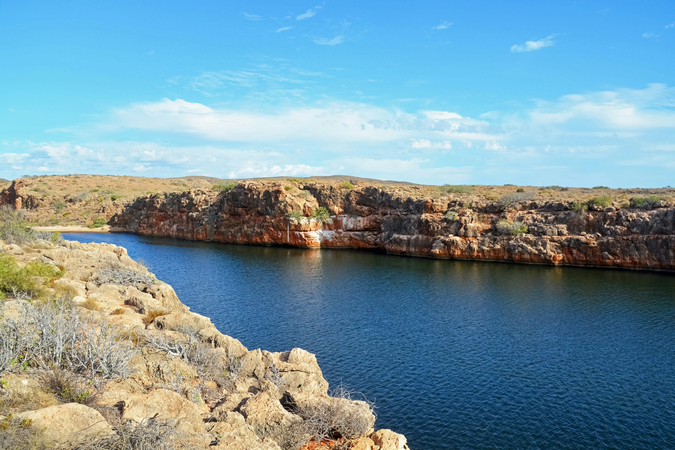 the lake is surrounded by rocky terrain near a dirt bank