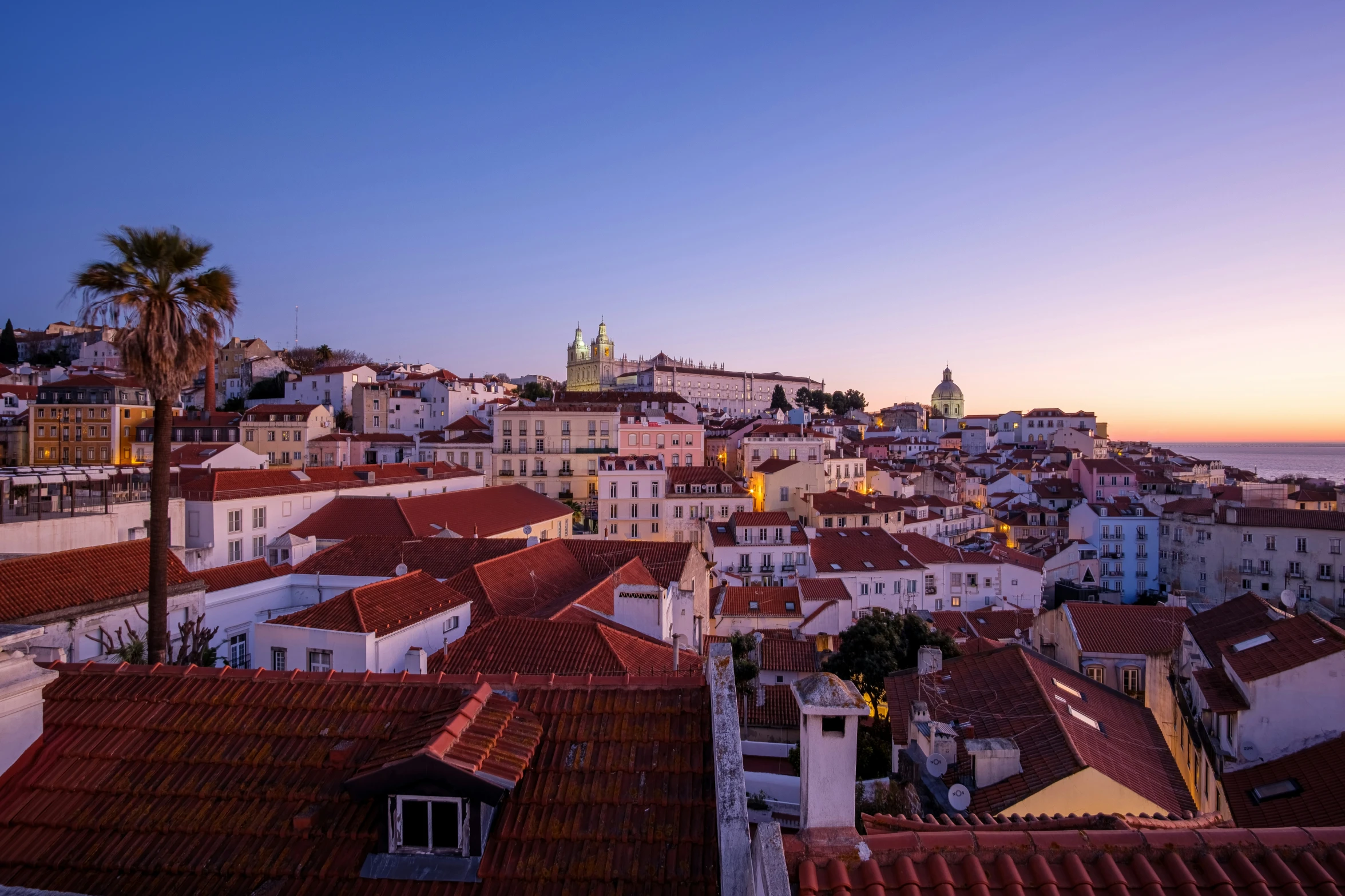 city rooftops at sunset, with an old bell tower in the distance