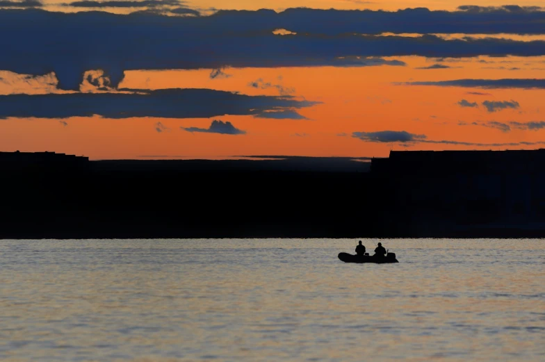 two people riding on a small boat in the water