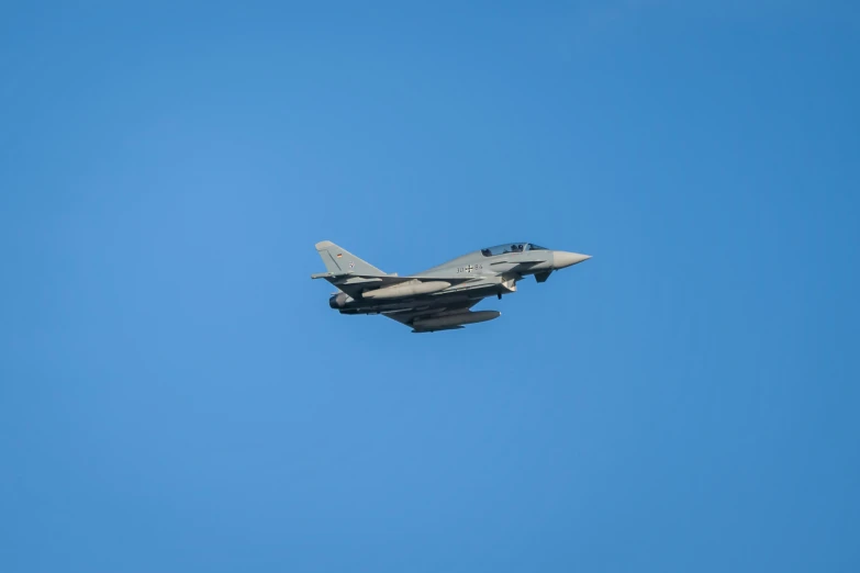 a military jet plane flies through the blue sky