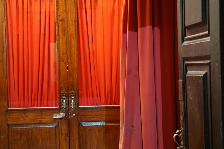 two red curtains hanging up in front of a door