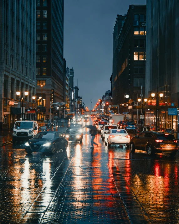 cars drive down a wet city street at night