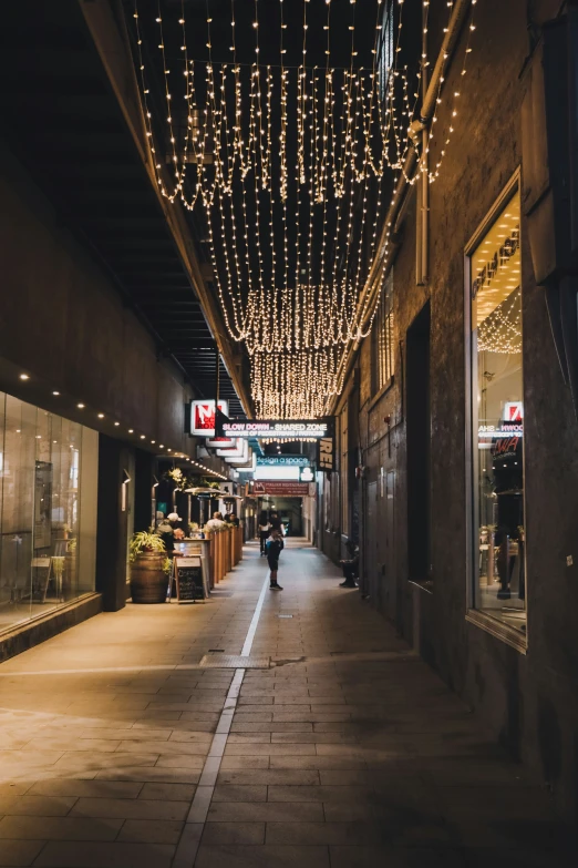 an empty sidewalk with some lights hanging from it