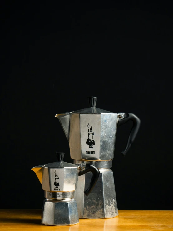 three metal coffee pots on a wooden table