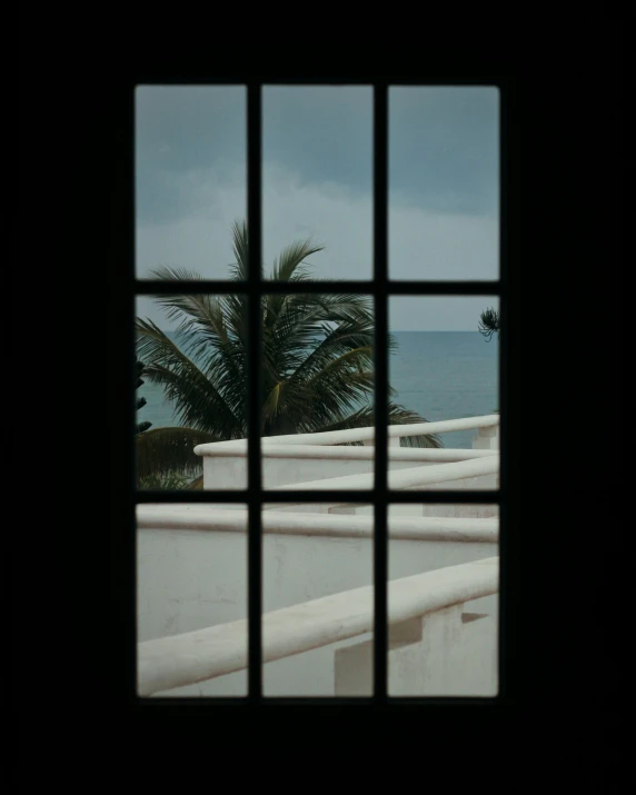 a window with a bird sitting on the ledge next to the ocean