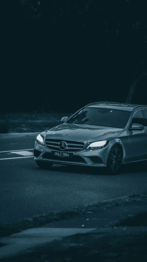 the front of a mercedes car driving down a street at night