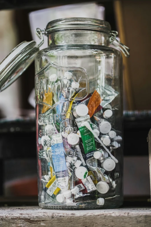 a jar full of plastic trash with a can in the back