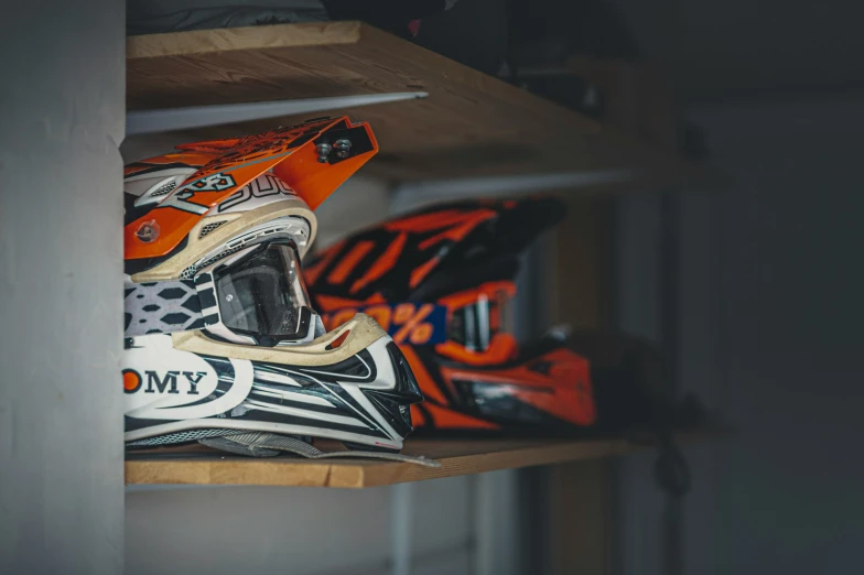 a pair of dirt bike helmets sitting on top of a shelf