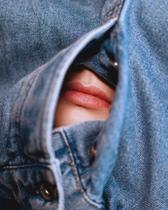 a man with his mouth open hiding behind some blue jean pants