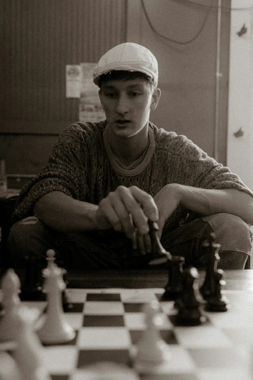 a young man sitting at a table with a chess board