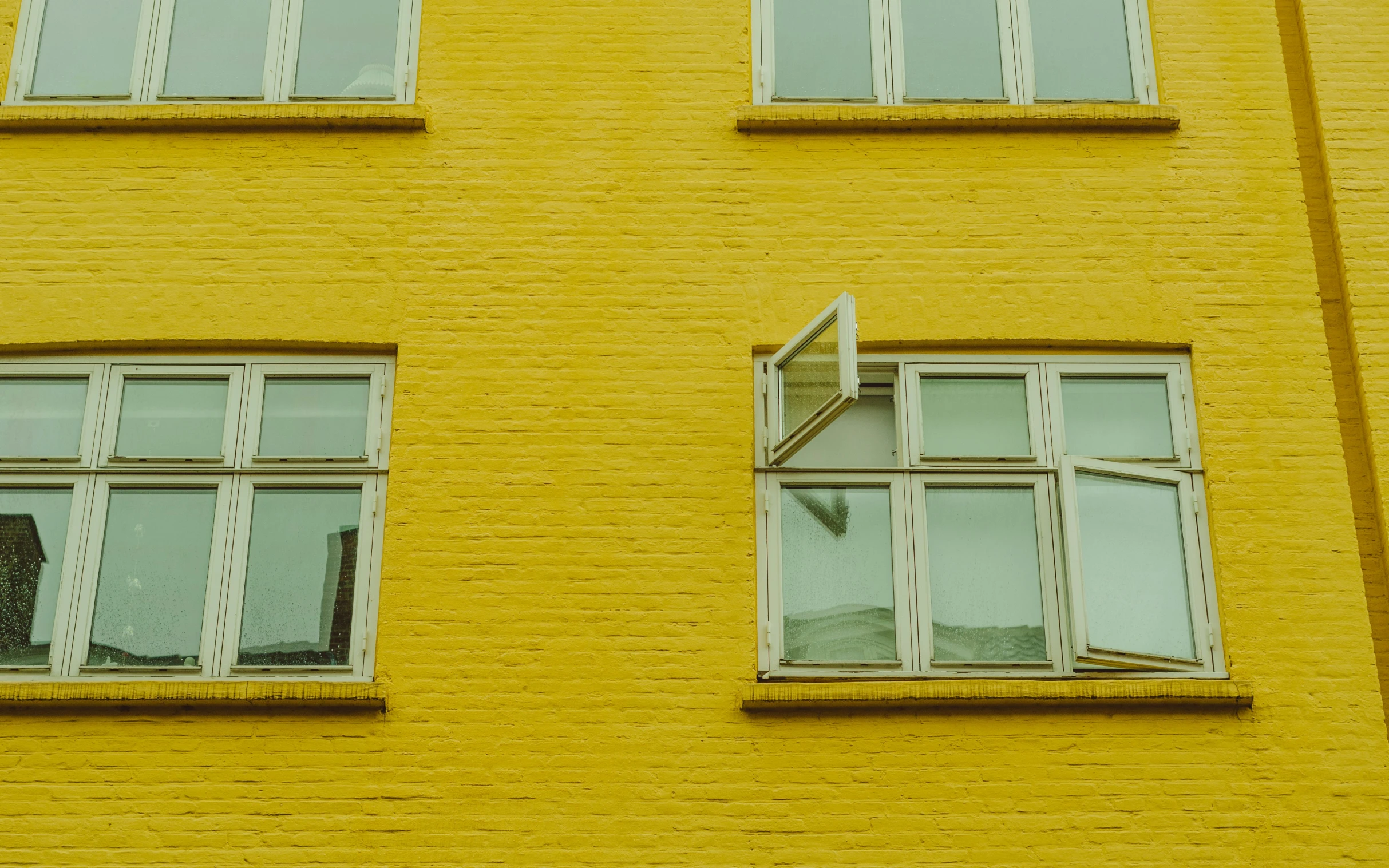 three windows at a yellow building that are closed