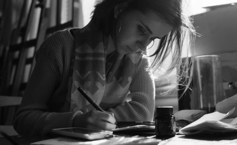 a girl writing in a book while holding her hand on her chin