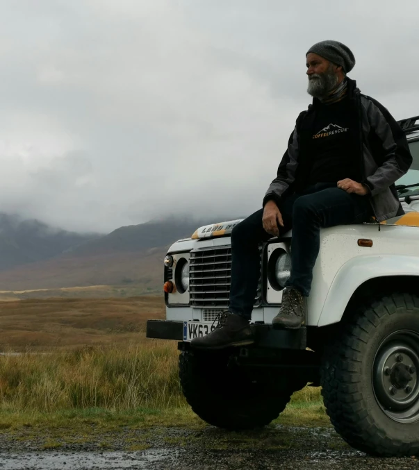 a man sitting on top of an old white truck