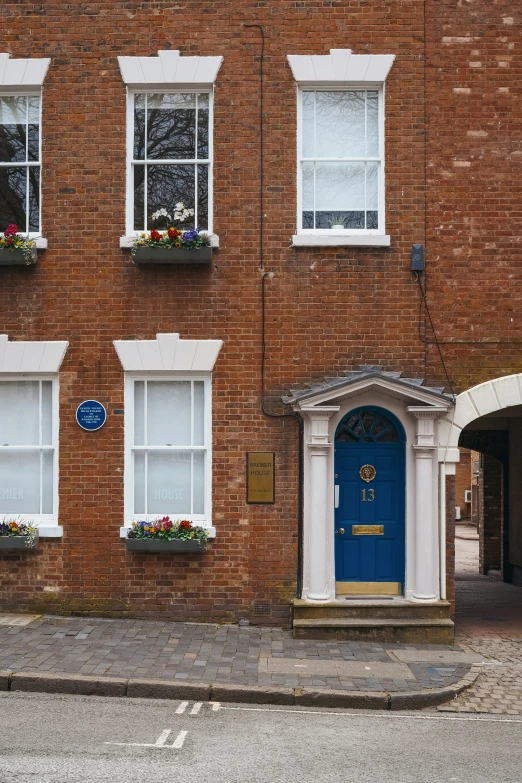 an old brick building with flower boxes on the front and blue door