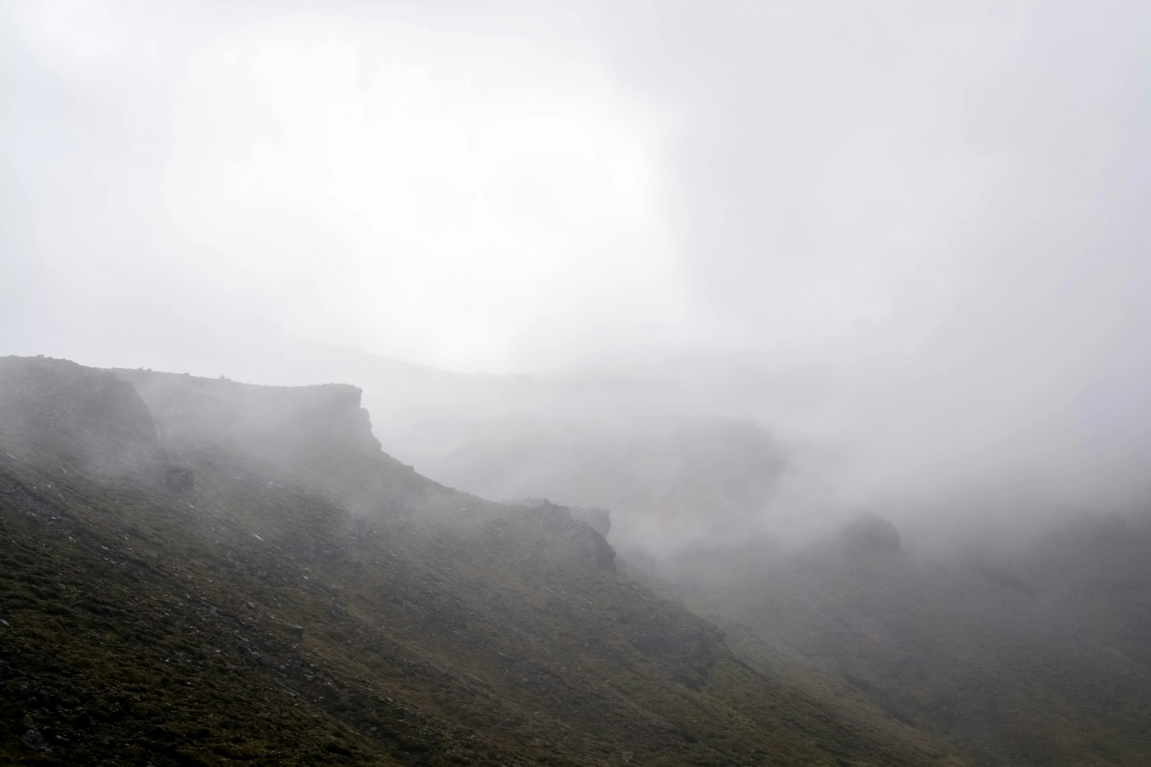 a dark foggy mountain with very low and steep peaks