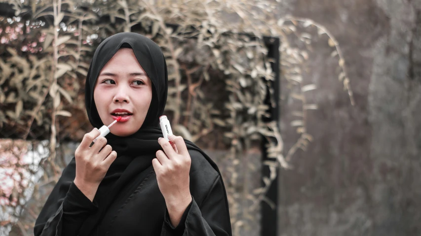 a woman with a scarf is holding two electronic devices