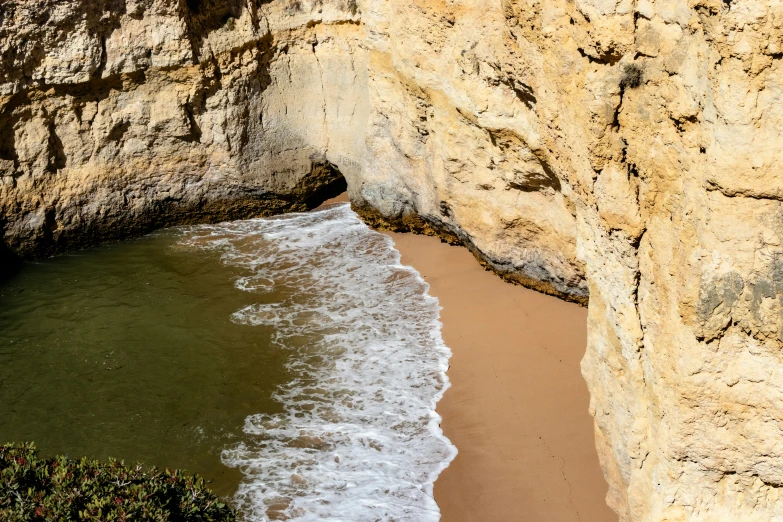 two small waves crashing onto the shore at a cliff