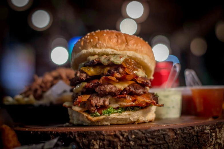 a large loaded meat sandwich on a wooden slab