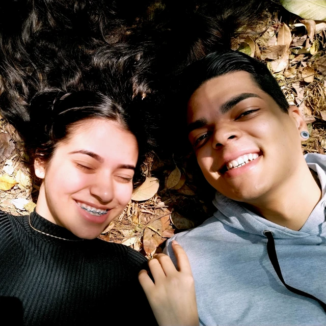two people lay on the ground together and smile