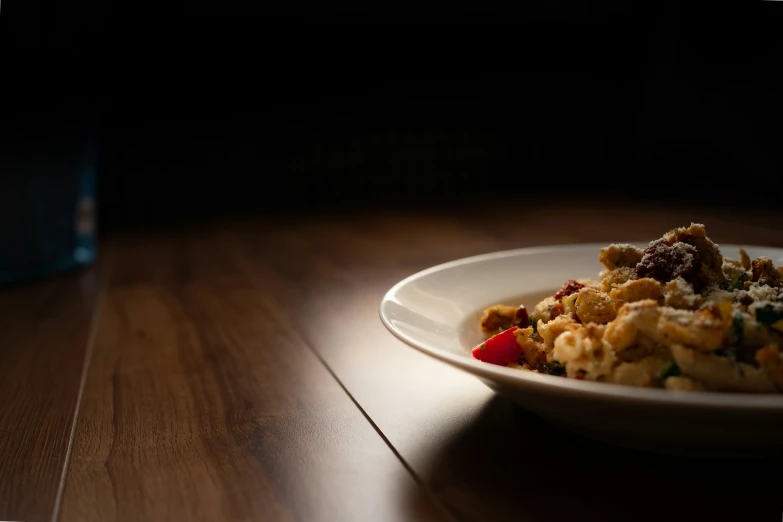 a white bowl of food on a wooden table