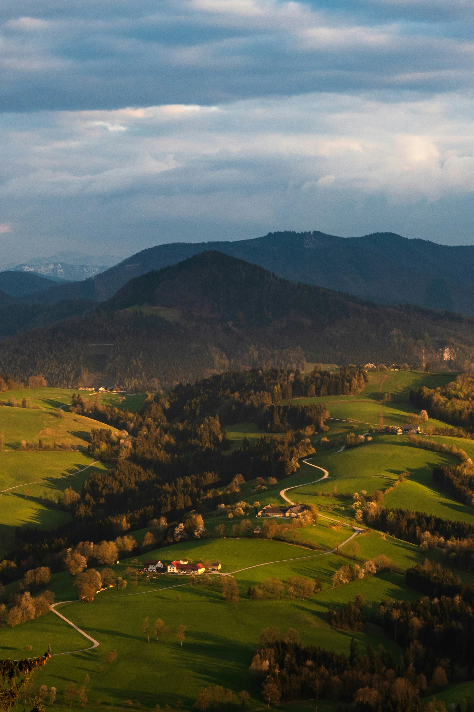 a valley sits at the foot of mountains under cloudy skies