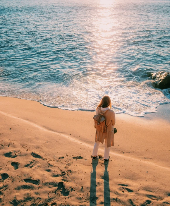 a person standing on the beach by the water