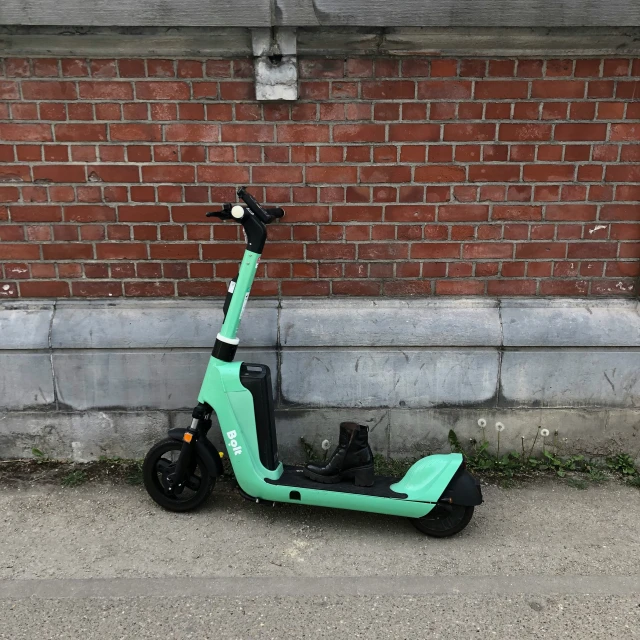 the scooter is green and black sitting on the sidewalk