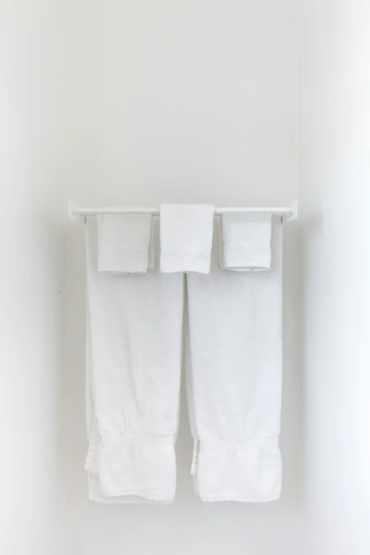 a white towel rack hangs on the wall and two white towels are folded