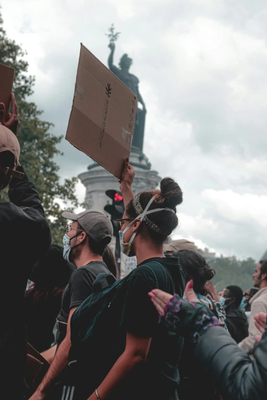 people standing and holding up signs in front of a statue