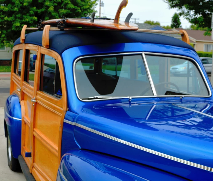 a car with surfboard on top, is parked in a driveway